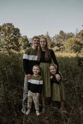 Famille en tenues coordonnées kaki et noir dans les hautes herbes en automne